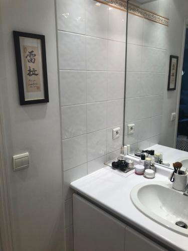 une salle de bain blanche avec un lavabo et un miroir dans l'établissement Apartment Trocadero/Eiffel Tower, à Paris