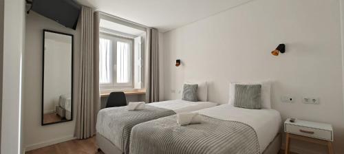リスボンにあるCorreio Velho Suites IIのベッド2台と鏡が備わるホテルルームです。