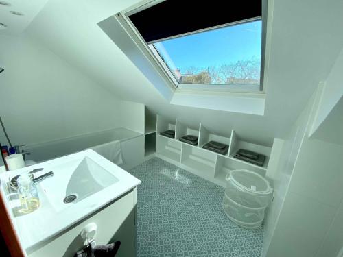 ein weißes Badezimmer mit Waschbecken und Fenster in der Unterkunft Magnifique 2 pièces Theatre de Boulogne in Boulogne-Billancourt