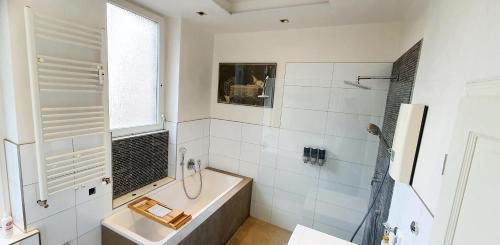 a white bathroom with a tub and a sink at Helles Zimmer mit Kingsize-Bett in Mannheim