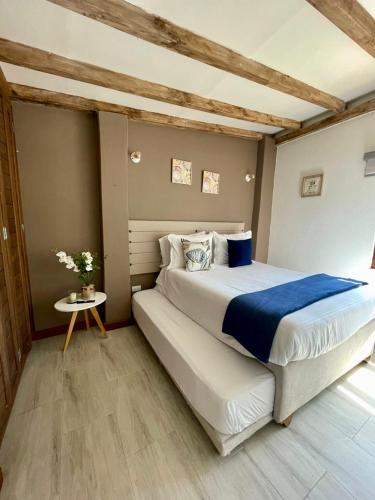 a bedroom with a large bed and a table at PUERTA DE LA VILLA Apartamentos y Habitaciones in Villa de Leyva