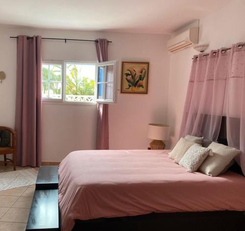 Sainte-Suzanne的住宿－La Villa d'Elyas，一间卧室配有一张带粉红色窗帘的床和窗户。