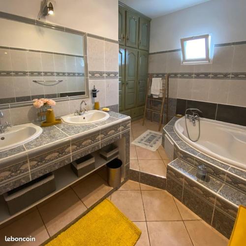 Sainte-Suzanne的住宿－La Villa d'Elyas，浴室配有2个盥洗盆、浴缸和浴缸。