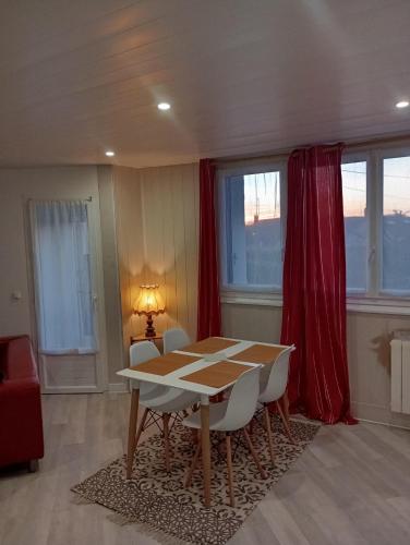 a dining room with a table and chairs and windows at Appartement confortable in Dreux