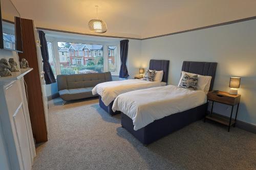 a bedroom with two beds and a couch and a window at Waves of Memories Rhos on Sea in Llandrillo-yn-Rhôs