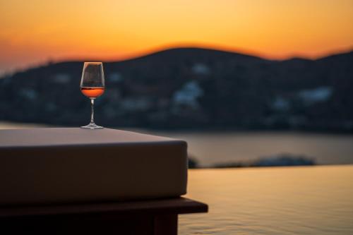 a glass of wine sitting on a table next to a laptop at Villa Mirabilis in Ios Chora