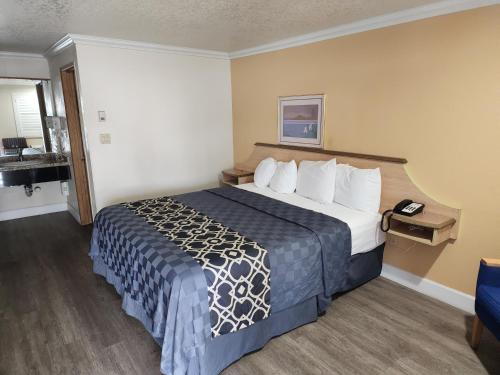 a hotel room with a large bed and a bathroom at Budget Inn in Corcoran
