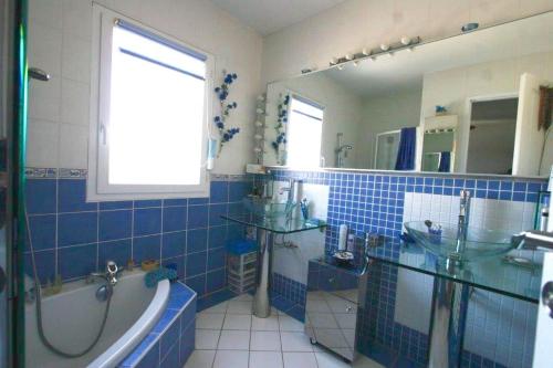 La salle de bains est pourvue de carrelage bleu, d'une baignoire et d'un lavabo. dans l'établissement Villa avec piscine. Plage à 300m, à La Grande Motte