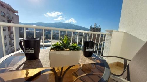 two coffee cups sitting on a table on a balcony at MINA modern & cozy apartment main city square GTC Skopje in Skopje