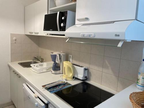 La cuisine est équipée d'un plan de travail, d'un évier et d'un four micro-ondes. dans l'établissement Appartement vue mer/piscine-Les pins bleus, à Juan-les-Pins