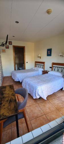 1 dormitorio con 2 camas, mesa y sidra de mesa en Hostal Mont-Rock en Montagut