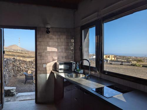 a kitchen with a counter with a sink and a window at Buena Vista, Sea View Apto de Oasis Vasiliko , La Asomada in Tías