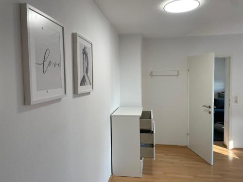 a white hallway with a white cabinet and pictures on the wall at Deluxe Urban Stay in Linz