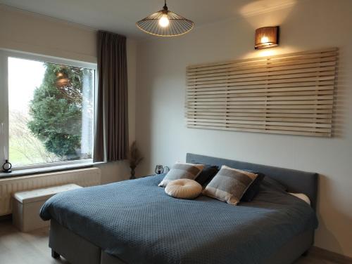 1 dormitorio con cama azul y ventana en Vakantiehuis 't Leideveld en Maarkedal