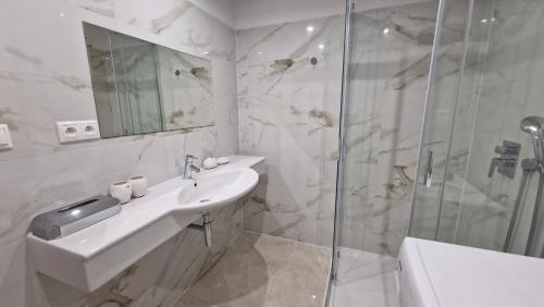 a white bathroom with a sink and a shower at Apartmány Drazdiak pri Nemocnici sv Cyrila a Metoda in Bratislava