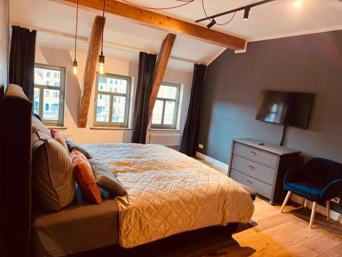 ein Schlafzimmer mit einem Bett, einer Kommode und einem TV in der Unterkunft MARKT LIFE HOME APPARTMENTS in Lutherstadt Wittenberg