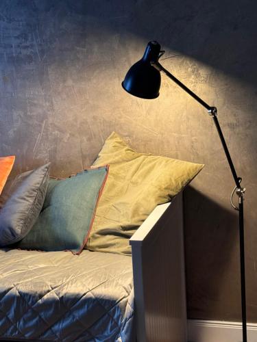 a black lamp sitting next to a bed with pillows at MARKT LIFE HOME APPARTMENTS in Lutherstadt Wittenberg