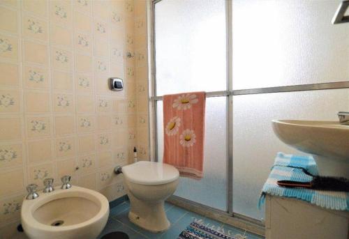 a bathroom with a toilet and a sink at Apartamento pé na areia com vista para o mar aberto in Guarujá