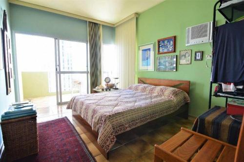 a bedroom with a bed with green walls and a window at Apartamento pé na areia com vista para o mar aberto in Guarujá