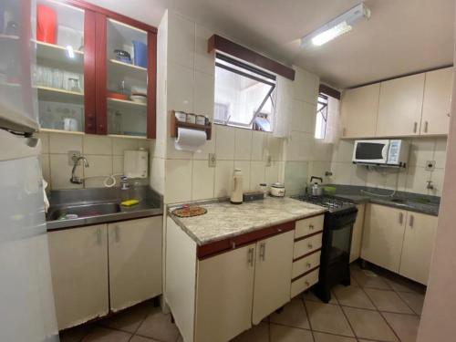 Elle comprend une petite cuisine avec des placards blancs et un évier. dans l'établissement Apartamento centro de BC, à Balneário Camboriú