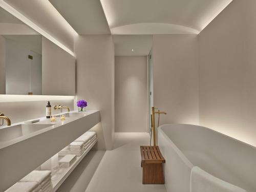 a white bathroom with a tub and a sink at The Singapore EDITION in Singapore