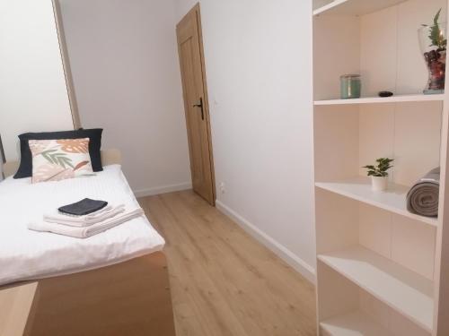 a small room with a bed and shelves at Apartamenty Jaskółcza in Bydgoszcz