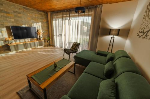 ein Wohnzimmer mit einem grünen Sofa und einem TV in der Unterkunft Apartmán C1 - Slovenský Raj in Hrabušice
