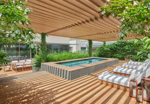 un patio con una piscina bajo una pérgola de madera en The Singapore EDITION, en Singapur