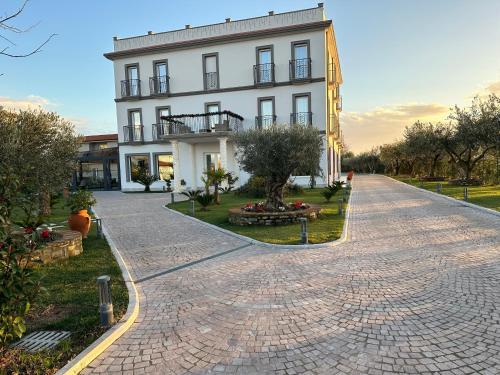 a large white building with a brick driveway at Evergreen Laguna Vain-Lezhe in Lezhë