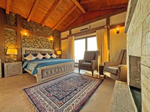 a bedroom with a bed and two chairs at Cedar Lodges Resort and Residences Galiyat in Chhāngla Gali