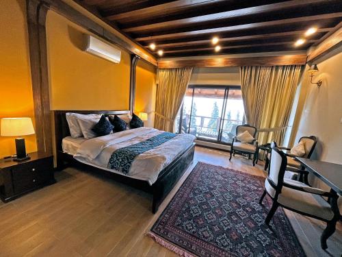 a bedroom with a bed and a table and a window at Cedar Lodges Resort and Residences Galiyat in Chhāngla Gali