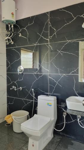 a bathroom with a white toilet and a black wall at The Inchara Hill View HomeStay in Chikmagalūr