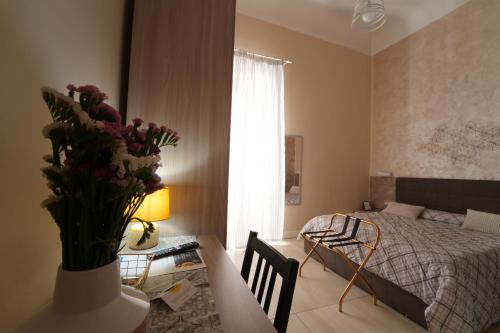 a bedroom with a bed and a table with a vase of flowers at CASA FELICE Suite Room in Taranto