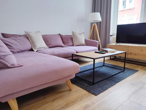 ein Wohnzimmer mit einem lila Sofa und einem Couchtisch in der Unterkunft 'BRIGHT 29' schöne, ruhige Innenstadtlage in Bielefeld, 400 m bis Klinikum Mitte, Smart TV, WLAN in Bielefeld