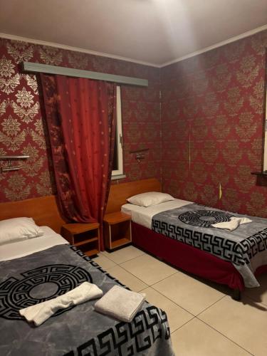 2 camas en una habitación con papel pintado de color rojo en Hôtel Rozafa, en Charleroi