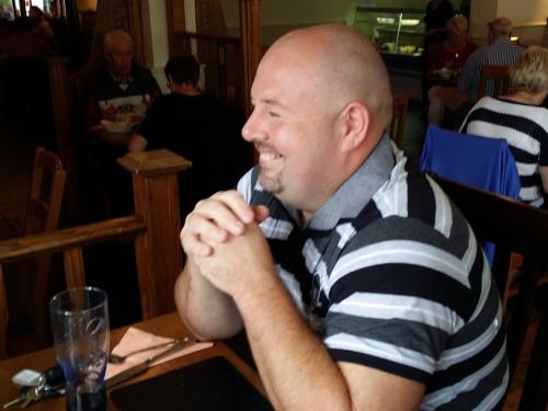 un hombre con una camisa a rayas sentado en una mesa en The Begelly Arms Hotel en Kilgetty