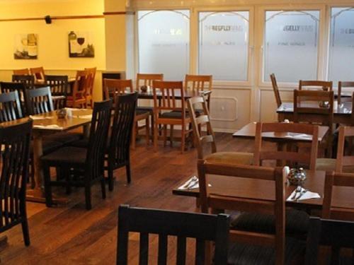 a restaurant with wooden tables and chairs and windows at The Begelly Arms Hotel in Kilgetty