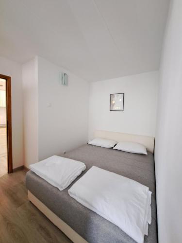 two beds in a room with white walls at Apartman Ena & Marta in Lovran