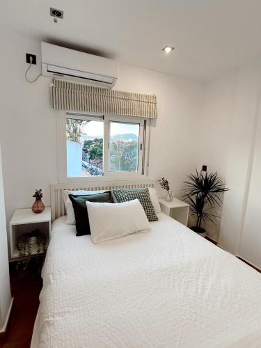 1 dormitorio con cama blanca y ventana en Cosy Trinidad, en Málaga