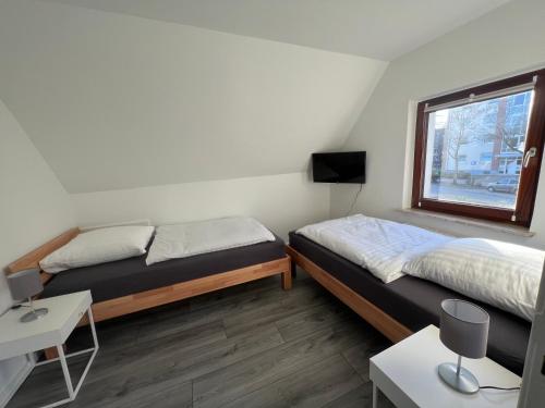 "Live Good, Work Good" Central House by GG Rental Hamburg في Schenefeld: سريرين في غرفة بها نافذة