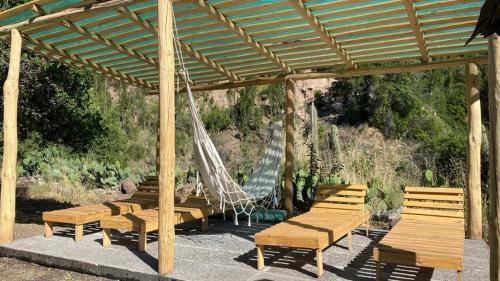 un grupo de bancos con una hamaca en un pabellón en Arte Vitral Lodge - 4camas- aislada- terrazas -vista - piscina-sauna en Guayacán