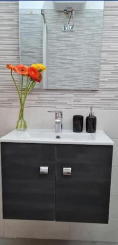 a bathroom sink with a vase of flowers on it at Little Home in Bolsena