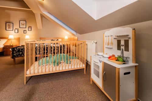 a childs room with a crib and a kitchen at Penzion Věžička in Lázně Bělohrad