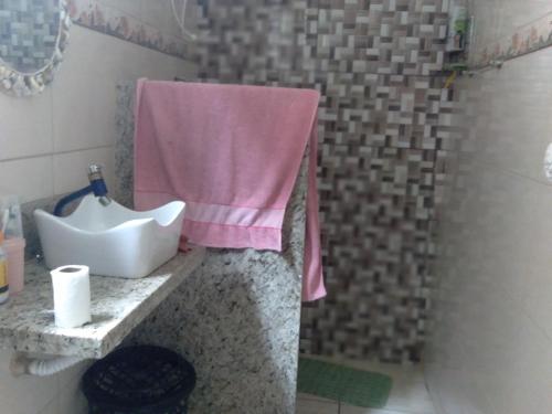La salle de bains est pourvue d'un lavabo et d'une serviette rose. dans l'établissement Casa de praia, à Angra dos Reis