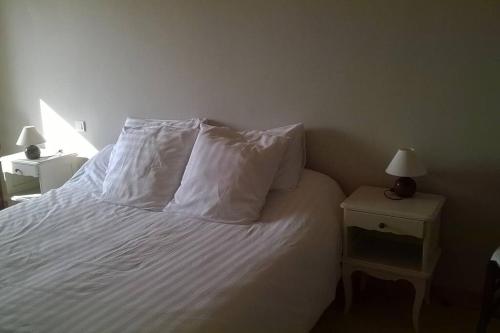 a bedroom with a bed with white sheets and pillows at La route bleue in Ploumilliau
