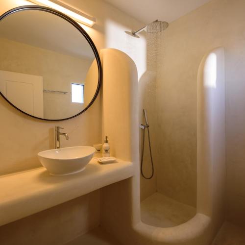 a bathroom with a sink and a mirror and a shower at Kamares Apartments in Fira