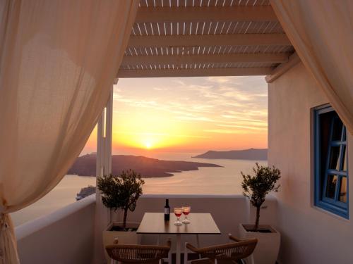 a table with wine glasses and a view of the sunset at Kamares Apartments in Fira