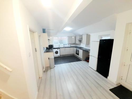 a kitchen with white cabinets and a black refrigerator at Double ensuite room in Leicester