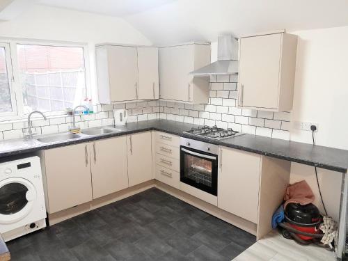 a kitchen with white cabinets and a stove top oven at Double ensuite room in Leicester