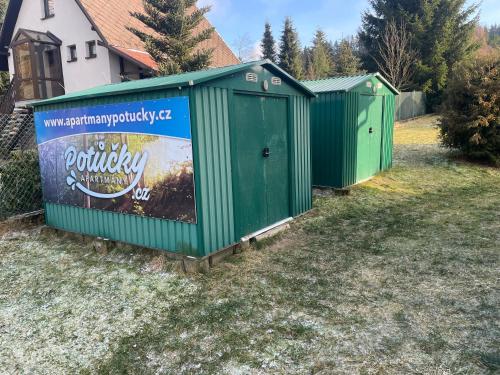 a row of green portable toilets in a yard at Apartmány Potůčky in Potŭčky